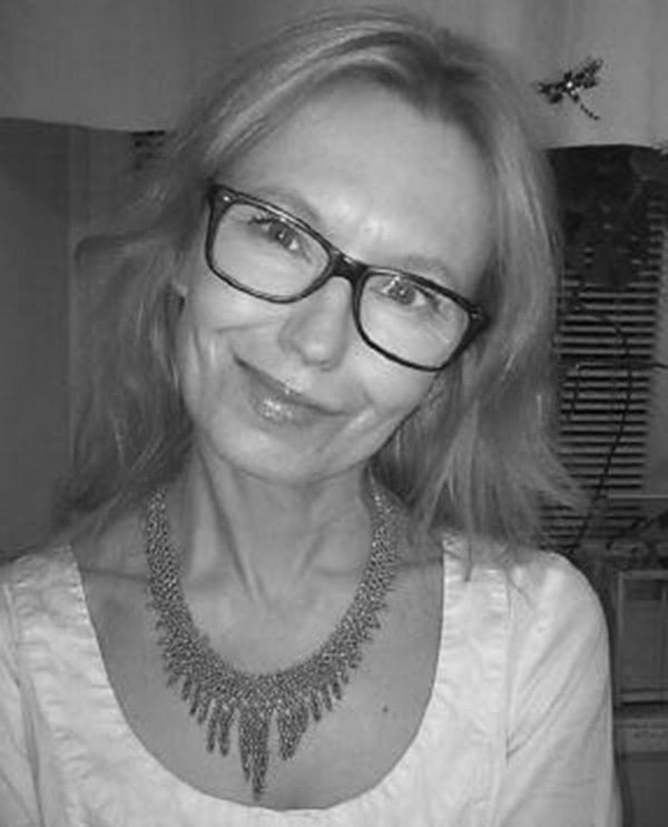 Zdjęcie portretowe kobiety w okularach w lekkim uśmiechu i blond włosach